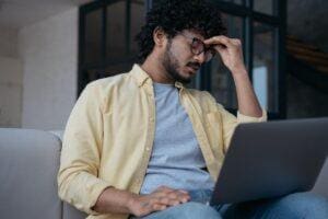 Man gets headache while looking at computer as he struggles with overthinking and anxiety