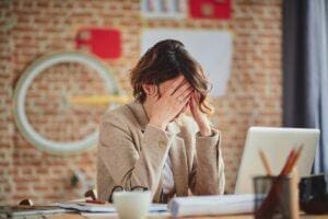 Woman sits at desk at thinks about OCD symptoms in women