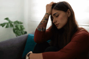 Woman dealing with traumatic grief struggles while sitting on couch