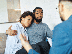 Man hugs his son during systemic family therapy