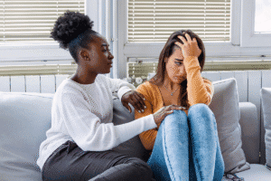Woman comforts friend on couch about depression and relationships