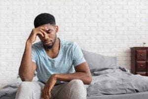 Man sits on bed while considering how to stop overthinking