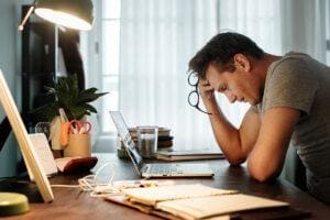 Man sits at desk as he grapples with both stress and depression