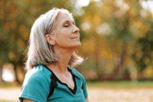 Woman sighs while walking in park after learning how to reduce emotional reactivity