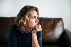 Woman sits on couch and considers what stimming is