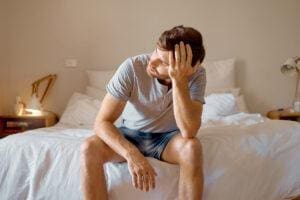 Person thinking about schizoaffective disorder vs. schizophrenia while sitting on bed